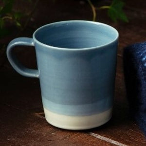 Blue and white mug on a dark background beside scarf and socks