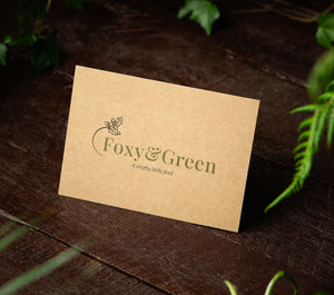 Foxy and Green gifts postard sitting on a dark background with greenery as a reflection to our dedication to eco-friendly and sustainability 