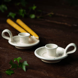 Eco-friendly and non toxic beeswax candles and two white ceramic candle holders on a dark background