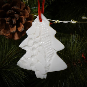 handcrafted ceramic christmas decoration sitting on tree with lights