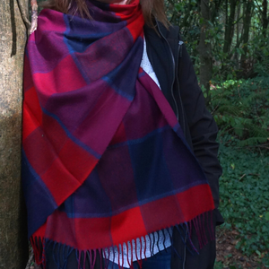 close up image of red and navy scarf draping on woman standing against tree