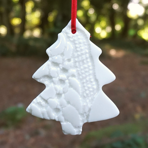 Cream christmas decoration hanging from a tree with red ribbon